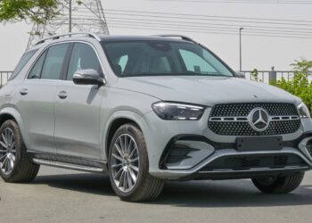 A silver Mercedes-Benz SUV parked near greenery and a metal fence, with power lines in the background—showcasing a top choice for those seeking the best car lease deals.