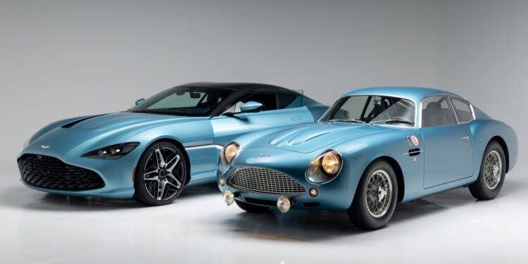 A modern blue Aston Martin DBS GT Zagato is parked beside a vintage DB4 GT Zagato Continuation coupe in a studio with a plain light background.