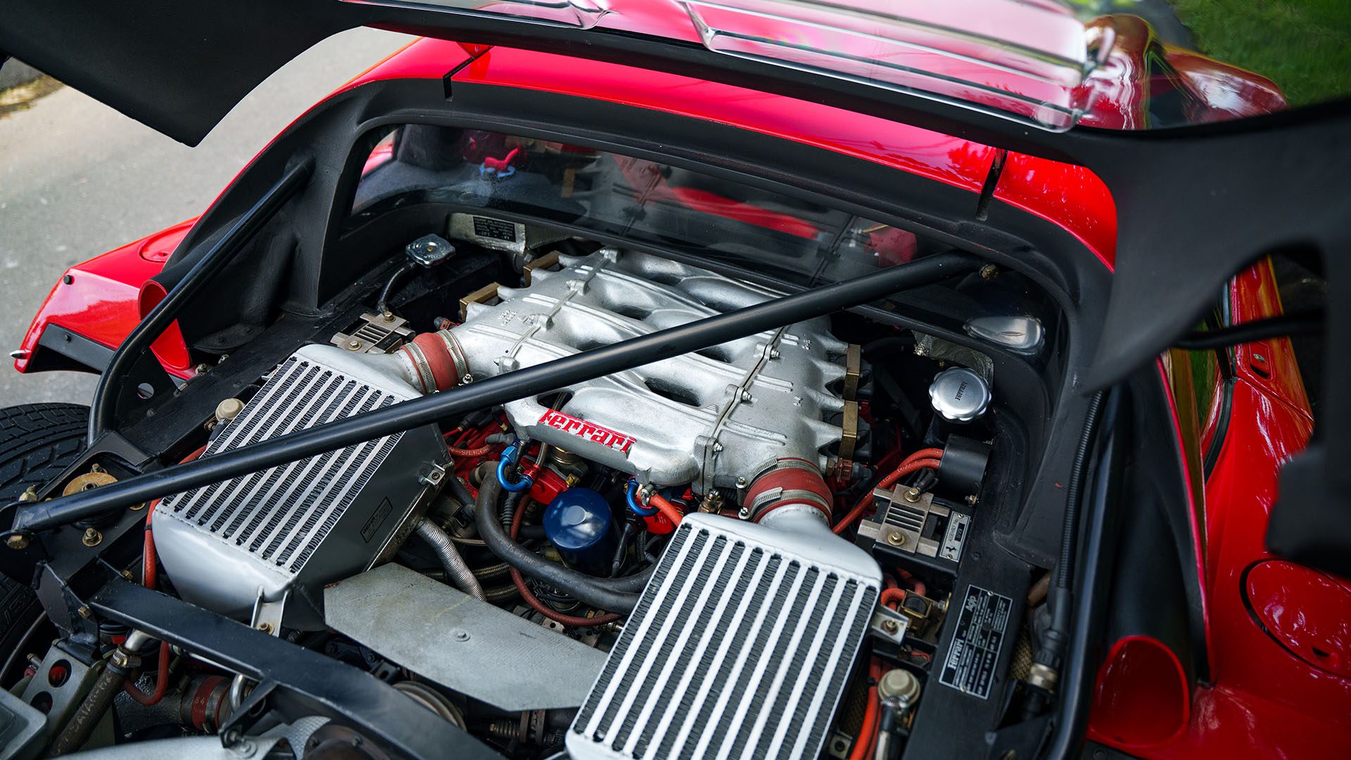 Close-up view of a 1991 Ferrari F40 engine with twin intercoolers and visible branding, hood open, showing detailed components—an iconic highlight from the Monterey Jet Center Auction by Broad Arrow.