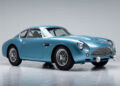 A light blue classic sports car with wire-spoke wheels, chrome details, and a distinctive grille, reminiscent of the DB4 GT Zagato Continuation, photographed in a studio setting.