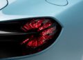 Close-up of a modern car’s red taillight with angular, geometric design against a light blue painted body, reminiscent of the style seen on the Aston Martin DBS GT Zagato at the Monterey Jet Center Auction.