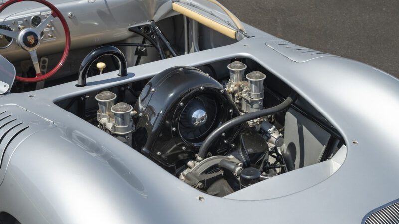 Close-up view of a classic Porsche 718 RSK Spyder’s exposed rear engine compartment, displaying intricate mechanical components and carburetors—captured ahead of the 2025 Monterey Jet Center Auction.