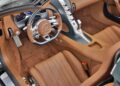Interior of a luxury sports car featuring tan leather seats, a modern steering wheel with the Bugatti logo, and metallic control elements on the center console—truly embodying The W16 Swan Song: Jay Leno Shares His Thoughts On The Bugatti Mistral.