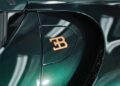 Close-up of a dark green Bugatti Mistral, its gold EB logo and glossy door reflecting light—capturing the elegance highlighted in The W16 Swan Song: Jay Leno Shares His Thoughts On The Bugatti Mistral.