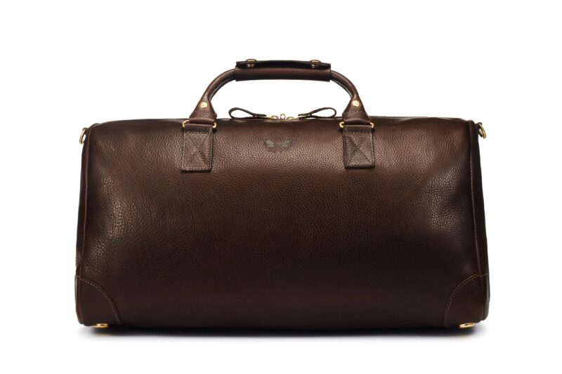 A large, rectangular dark brown leather duffle bag with two handles, gold hardware, and a small embossed logo on the front—perfect for anyone seeking a style upgrade with luxury accessories.