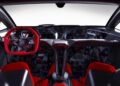 Interior view of a sports car featuring minimalist design, red and black steering wheel, and carbon fiber accents throughout the dashboard and seats—just like The Only Street-Legal Lamborghini Sesto Elemento that wows Goodwood.