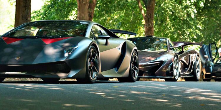 Two high-performance sports cars, including a street-legal Lamborghini Sesto Elemento in matte black, are parked under leafy trees on a sunlit road.