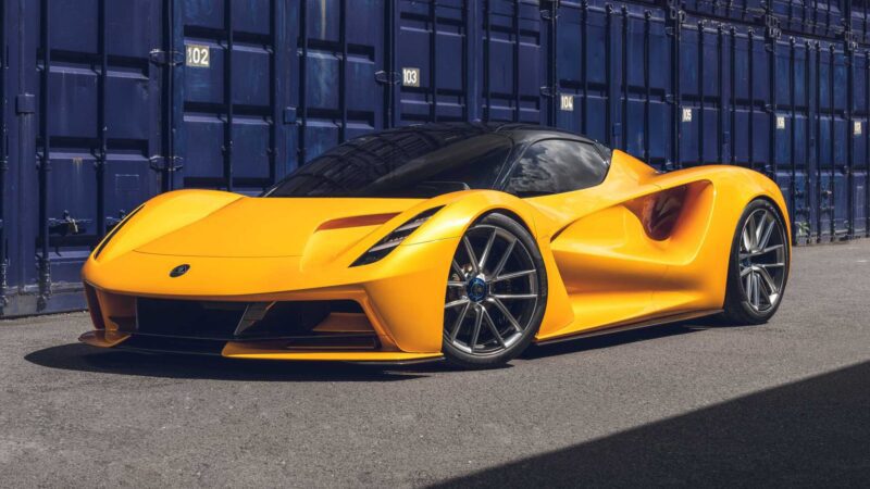 A yellow sports car with a sleek aerodynamic design—one of the most powerful production cars—sits parked on a paved surface in front of blue shipping containers.