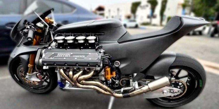 A bespoke superbike with a massive exposed Ferrari V8 engine stands parked outdoors on two wheels, surrounded by cars and buildings in the background.