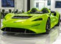 A bright green McLaren Elva, one of the most expensive McLarens, is displayed indoors on a glossy floor—an iconic example of luxury sports cars with no windshield.