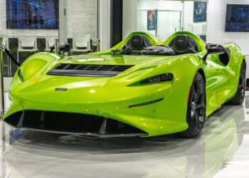 A bright green McLaren Elva, one of the most expensive McLarens, is displayed indoors on a glossy floor—an iconic example of luxury sports cars with no windshield.