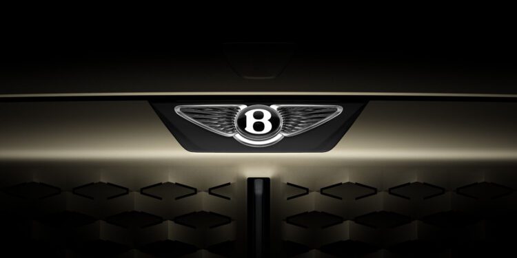 Close-up of the front grille of a car featuring the illuminated Bentley logo with a dark, shadowed background.
