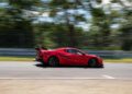 A red Corvette ZR1 with a large rear wing speeds along a racetrack, its blurred background emphasizing motion and evoking the thrill of one of the fastest American production cars chasing a Nürburgring record.