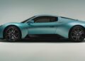 A matte blue 2026 Maserati MCPURA, debuting at Goodwood with a liquid crystal roof and F1 tech, is shown in profile against a plain light background.