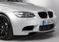 Close-up of the front left side of a silver BMW E90 M3, showing the headlight, grille, license plate, and black wheel against a plain background—a desirable collector car for enthusiasts.