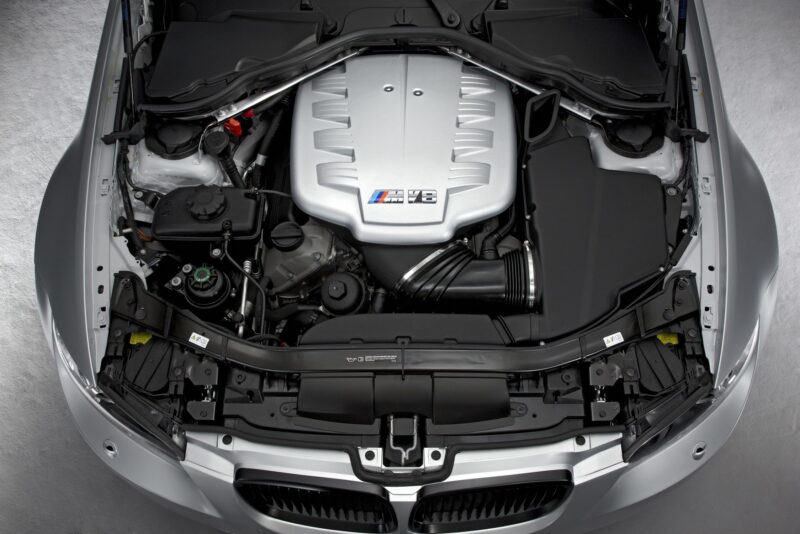 View of a BMW E90 M3 engine bay with a silver M V8 engine cover, showcasing various components from above—a true collector car worth over $250K to the right enthusiast.