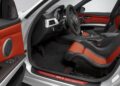 Interior view of a BMW E90 M3 Collector Car showing the driver's seat, steering wheel, dashboard, and red-and-black leather upholstery—a true standout, valued at up to $250K.