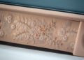 Close-up of a Rolls-Royce Phantom Dentelle interior panel with intricate floral embroidery on beige leather and a blue leather seat above, showcasing the craftsmanship of this one-off masterpiece.