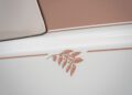 Close-up of a beige and white surface with a decorative leaf design and straight accent line, likely part of a one-off Rolls-Royce Phantom Dentelle.