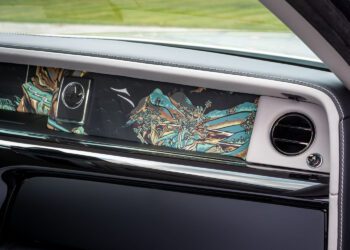 Close-up of a Rolls-Royce dashboard featuring a clock, air vent, and decorative panel with a colorful landscape inspired by bespoke Chinese murals of mountains and trees.