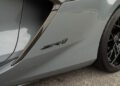 Close-up of a gray 2025 Chevrolet Corvette ZR1's side panel showing a "ZR1" badge near a black alloy wheel and carbon fiber trim.
