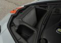 Close-up view of the 2025 Corvette's front trunk (frunk) area, highlighting a large air intake or radiator, with surrounding plastic trim and part of a coolant reservoir cap—showcasing Chevrolet Corvette ZR1 engineering.
