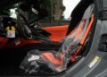 Interior of a new 2025 Chevrolet Corvette ZR1 for sale, featuring an orange driver's seat covered in protective plastic and a key tag hanging from the steering wheel.
