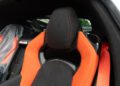 Close-up of a 2025 Chevrolet Corvette ZR1 seat with orange accents, black headrest featuring an embossed logo, and an orange seatbelt—showcasing the style of this 1,064HP supercar now for sale.