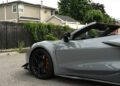 Gray 2025 Chevrolet Corvette ZR1 convertible sports car with black rims parked on a street, partially shown, with a house and greenery in the background—064HP,1 and now available for sale.