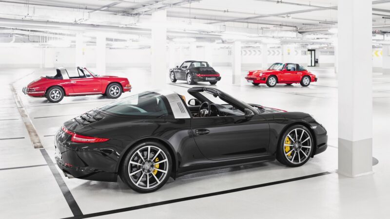 Four Porsche 911 Targa cars in different colors are parked in a modern indoor parking garage with white floors and walls, ready to turn heads at any auction.