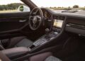 Porsche car interior of a 2016 Porsche 911 R showing the dashboard, steering wheel, manual gear shift, touchscreen display, and front seats with patterned upholstery.
