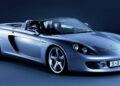 A silver Porsche Carrera GT convertible sports car, showcased against a dark blue background, captures the spirit of innovation—perfect inspiration for a tribute capsule collection.