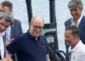 Four men, dressed in business casual attire, stand together on a boat near the water, smiling and conversing about the Porsche Macan EV-Powered Frauscher Fantom 850 setting a new speed record in Monaco.