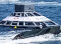 A black Porsche Macan EV-powered Frauscher Fantom 850 motorboat passes a large inflatable buoy marked "Monaco Energy Boat Challenge," setting a speed record in Monaco.