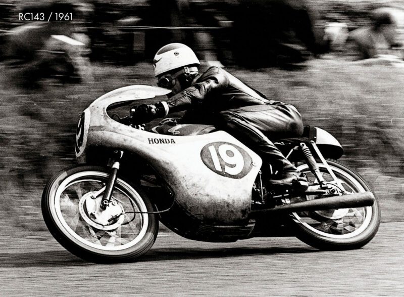 Black and white photo of a motorcyclist racing a Honda RC143 with the number 19 on its side, taken in 1961.