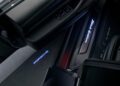 Open car doors reveal the illuminated "Porsche" logo on the floor and "Black Edition" text on the door sill, highlighting the exclusive 2026 Taycan in a dimly lit setting.
