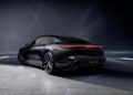 A sleek 2026 Porsche Taycan Black Edition sports sedan is shown from the rear at an angle, parked indoors under dramatic lighting that highlights its modern design and LED tail lights.