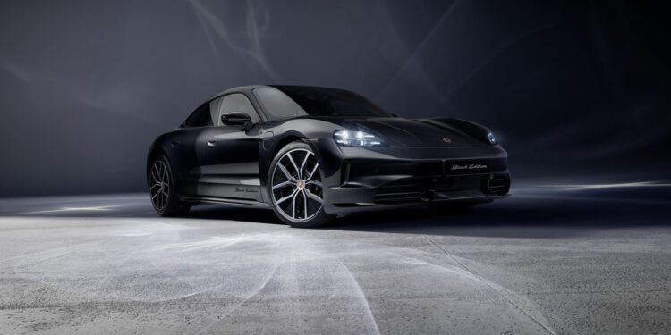 A 2026 Taycan Black Edition Porsche sports car is parked on a smooth, light-gray surface with a dark, gradient background.