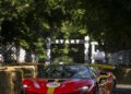 A red Ferrari race car speeds down the tree-lined Goodwood track, hay bales lining the F80 Hillclimb course, with a "START" sign visible in the background.