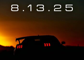 A sports car is silhouetted against a sunset with its taillights on; large text above reads "8.13.25". “The Next One”: Shelby’s Mysterious Mustang Set for Monterey Reveal.