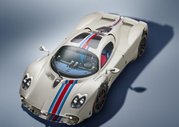 A white sports car with blue and red racing stripes, two seats, and aerodynamic design, photographed from above on a neutral background.