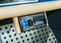 Close-up of a car dashboard featuring climate control dials, a digital Alpine audio system with blue buttons, and a perforated metal footrest—signature details in a Theon Design Air-Cooled 911.