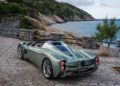 A silver Pagani convertible sports car parked on a stone-paved area near the coast, with rocky cliffs and the ocean in the background—evoking the thrill of upcoming hillclimb runs at Goodwood FoS 2025.