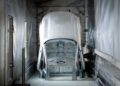 A car body shell is partially submerged in a liquid bath, likely as part of an industrial coating or painting process inside a factory booth, similar to advanced methods Volvo will use as it expands U.S. operations with XC60 production from 2026.