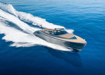 A modern luxury yacht moves quickly across calm, deep blue water, leaving a white trail behind it and showcasing the ultimate maritime experience.