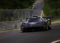 A black Pagani sports car speeds around the race track, capturing the excitement of the 2025 Monterey Car Week.