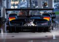 A high-performance Pagani sports car is parked indoors, viewed from the rear, showcasing its large rear wing, exposed exhausts, and aerodynamic features at the 2025 Monterey Car Week.