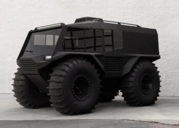 An amphibious, matte black Atlas ATV with oversized tires is parked on a concrete surface in front of a white brick wall—an impressive off-road vehicle for sale.