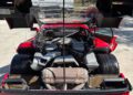 Rear view of a 1990 Ferrari F40 with its engine bay exposed, revealing powerful engine components, tires, and the open rear hatch—an iconic supercar ready for auction.