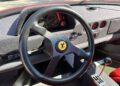 Close-up of a Ferrari F40 steering wheel, dashboard with gauges, control switches, and manual gearshift lever inside a classic car—ready for auction or buy it now opportunities.